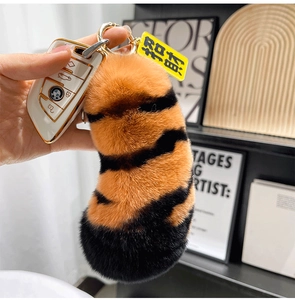 Macro detail of plush tiger tail keychain with golden clip and fortune tag on car keys