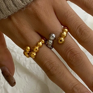 Close-up of minimalist gold and silver beaded stacking rings in a wave design