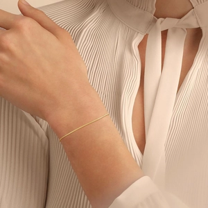 Close-up of 1mm minimalist gold stainless steel snake chain bracelet on a model wrist