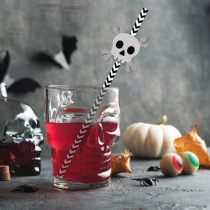Close-up of silver glitter skull decoration on striped straw in a Halloween drink