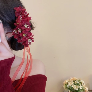 Detail of red floral hair pin with ribbons worn on a bun for an elegant hairstyle