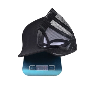 Detail view of a black mesh ponytail baseball cap on a digital scale weighing 77g