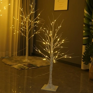 Detail showing artificial white birch tree lamps with warm LED lights on a square base