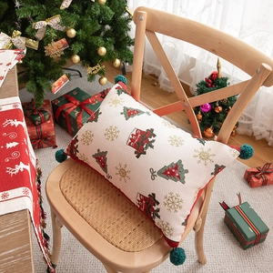 Close-up of festive Christmas cushion with tree patterns and green pom-poms on a chair