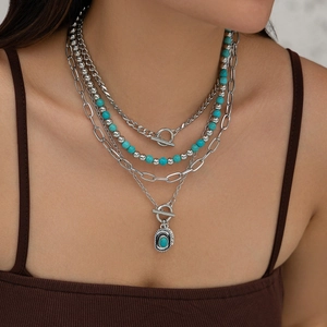 Detail of layered turquoise necklaces with bull head and cactus pendants in retro style