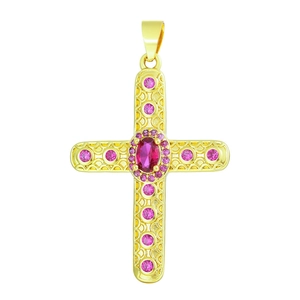 Golden cross pendant with pink gemstones and red oval center stone on white background