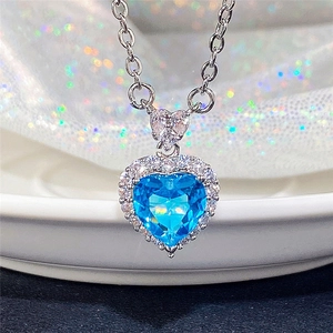 Close-up of heart-shaped blue topaz pendant with silver chain and crystal halo