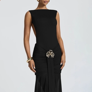 Detail of elegant black backless dress featuring a decorative gold flower buckle and pleats