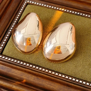 Detailed close-up of golden teardrop earrings on green fabric inside a vintage box