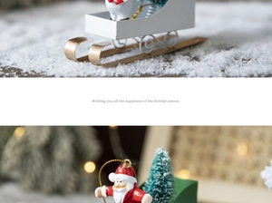 Close-up of a miniature white sleigh with Santa Claus and a small Christmas tree on snow