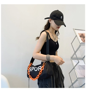 Détail du sac bandoulière en nylon noir avec chaîne orange et logo Sport sur modèle