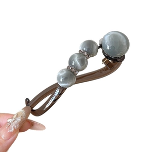 Acrylic resin hair clip with grey cat-eye beads and rhinestones shown in hand