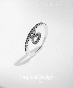 Macro detail of S925 silver heart charm ring with black pave stones on white background