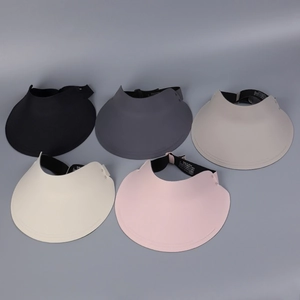 Flat lay of multiple summer sun visors in black, grey, cream, and pink with elastic bands