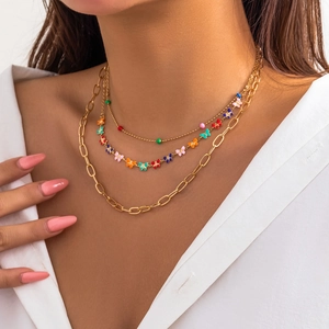 Close-up of layered gold chain necklace featuring colorful beads and butterfly pendants