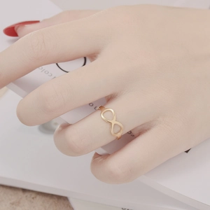 Close-up of a minimalist gold infinity ring worn by a model in a lifestyle setting