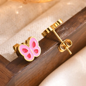 Macro shot of pink and red enamel butterfly earrings on a gold metal base