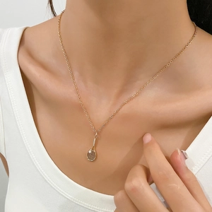 Detail of gold tennis racket pendant with micro-inlaid stones and a small pearl accent