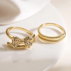 Luxury 18K gold plated bow ring set with sparkling zircons on elegant white ceramic stand