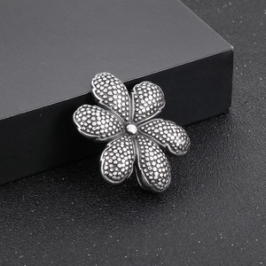 Macro shot of silver flower pendant with dot texture and polished metal details