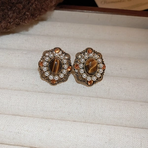 Detail view of retro earrings with tiger eye stone and small pearls on bronze base