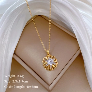 Macro shot of gold floral pendant with clear zircon inlay on a beige jewelry box