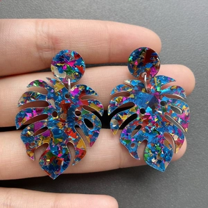 Detailed view of colorful acrylic monstera leaf earrings with shiny glitter foil flakes