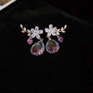 Detail of flower stud earrings with sparkling purple teardrop crystals and gold finish