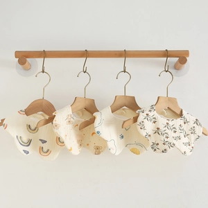 Detail of four petal-shaped organic cotton baby bibs with cute rainbow and animal prints