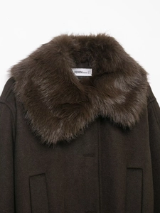Close-up of a dark brown wool coat featuring a plush faux fur collar and branded inner neck tag