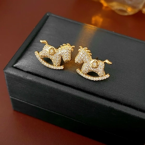 Macro shot of gold-plated rocking horse earrings with sparkling cubic zirconia on black box