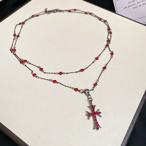 Detail of vintage gothic double-layer necklace with red gemstones and cross pendant