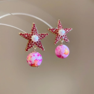 Detailed shot of star earrings with pink rhinestones and marble textured beads