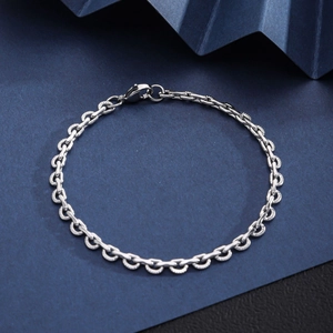 Close-up of silver Cuban link bracelet with lobster clasp on dark blue background