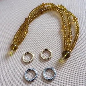 Detailed view of amber acrylic bead chain strap with gold and silver metal ring clasps