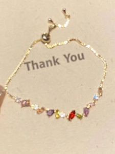 Detail of adjustable gold-plated chain bracelet with colorful pear-cut zircons