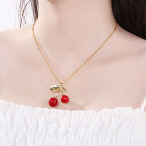 Elegant gold chain necklace with red cherry pendant worn on female collarbone
