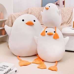 Soft white duck plush toy with orange beak and feet displayed in a cozy home setting
