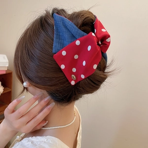 Detail of red polka dot and denim blue fabric bow clip worn on a high ponytail