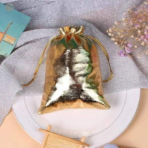 Detail of a shiny gold drawstring jewelry pouch on a white plate with decorative accents