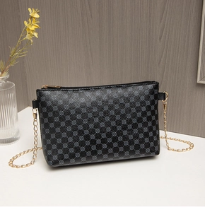 Detail of black synthetic leather crossbody bag with gold chain and round pattern