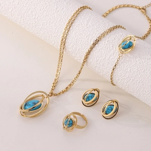 Close-up of gold jewelry set with oval blue turquoise stones on white pedestal