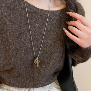 Detail of silver cross pendant with brown tiger eye texture on a sleek metal chain