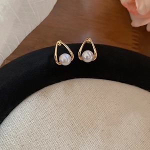 Detailed close-up of gold pear-shaped teardrop earrings with central white pearls