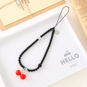 Handmade phone strap with black beads and red cherry pendants on aesthetic background