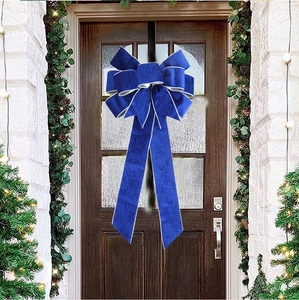 Detail showing a navy blue velvet Christmas bow with silver trim on a festive door wreath