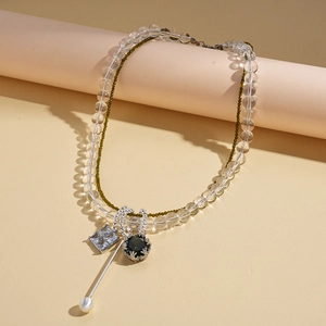 Detail of layered necklace with green gemstone, square crystal and white pearl pendants