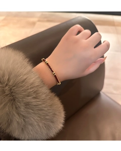 Dettaglio bracciale in pelle intrecciata rossa e oro con polsino in pelliccia