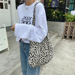 Detail of trendy leopard print canvas tote bag carried by model in casual street style
