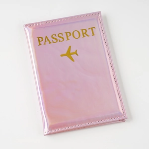 Vista detallada de la funda de pasaporte rosa holográfica en PU con texto dorado